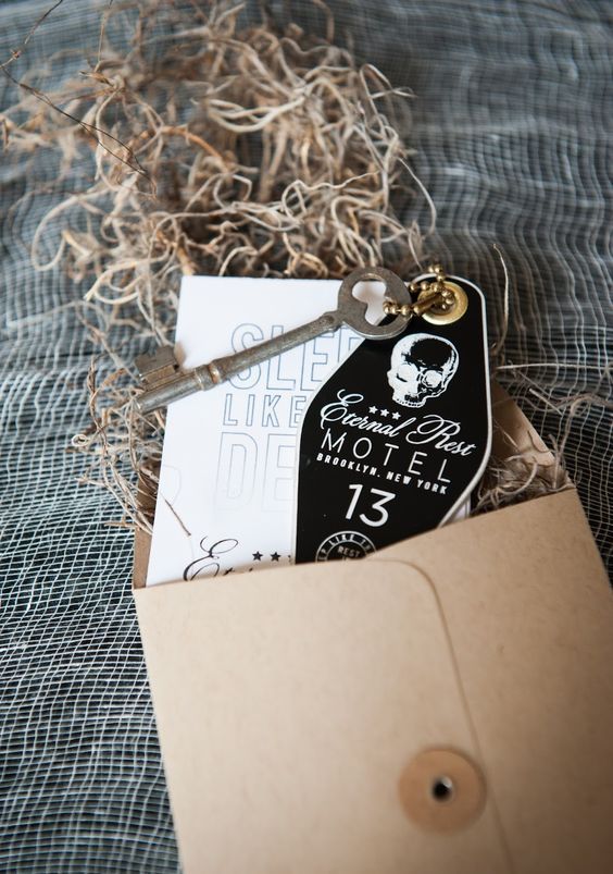 a kraft paper envelope, black and white coffin shaped invites and a vintage key for a Halloween party