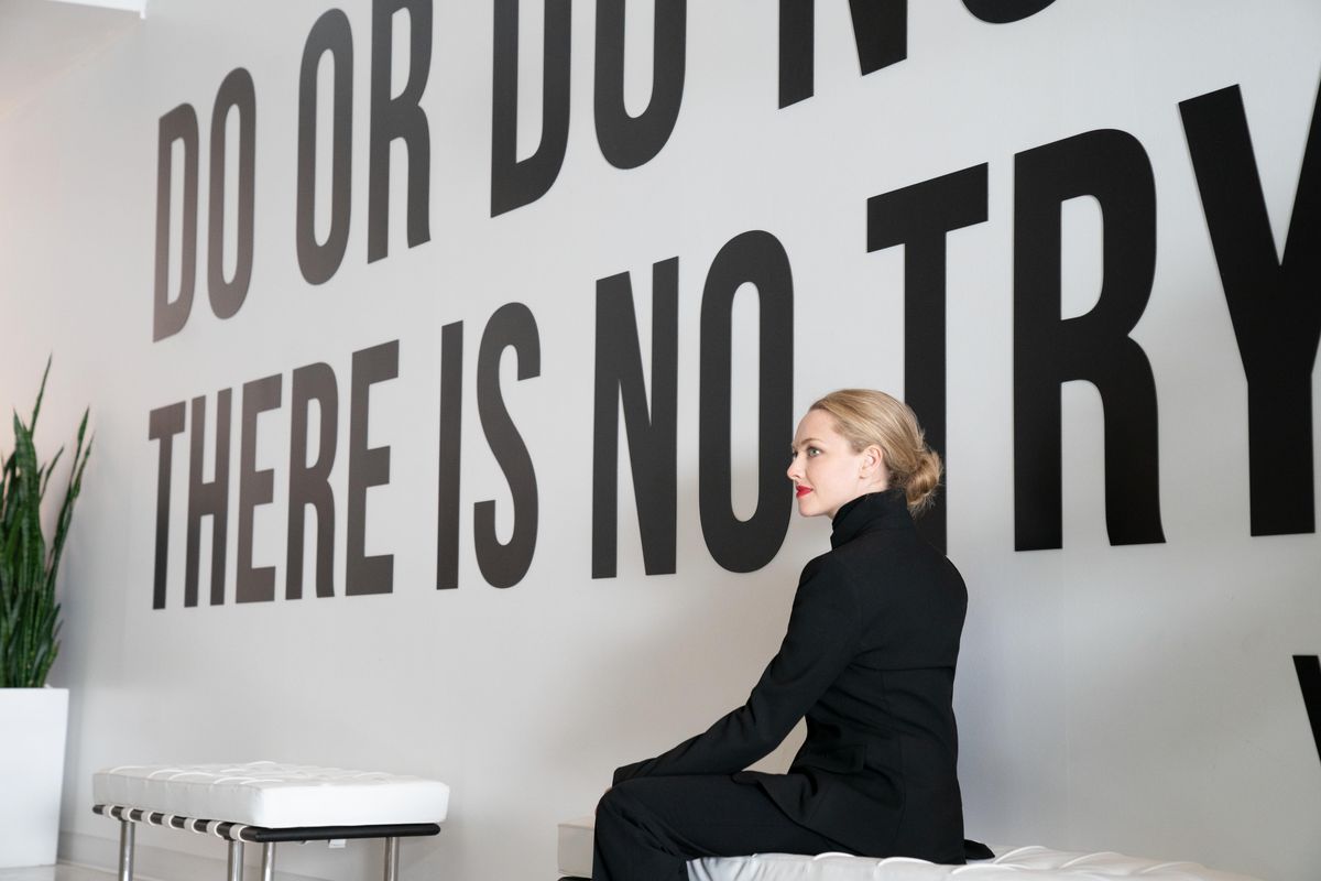 Elizabeth Holmes, played by Amanda Seyfried, sits in front of a the slogan “Do or do not. There is no try.”