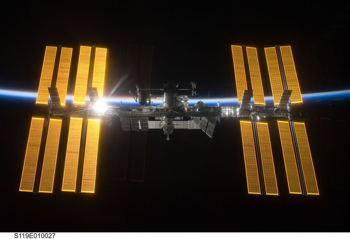 The ISS in space with the earth horizon curving behind it.